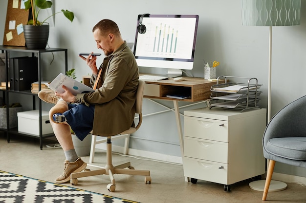 事務所の職場で文書を読んで記録している義足を持つ男の側面図の肖像画