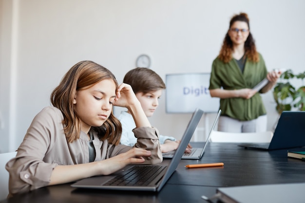 Side view portrait of schoolkids using laptops in IT class, copy space