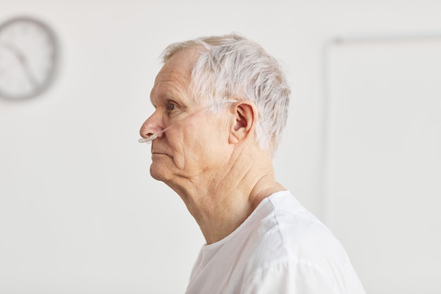 Side view portrait of senior man in hospital with focus on oxygen support tubes, copy space