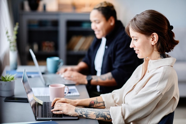 Foto ritratto di vista laterale di due donne che utilizzano computer a casa sul posto di lavoro insieme copiano lo spazio