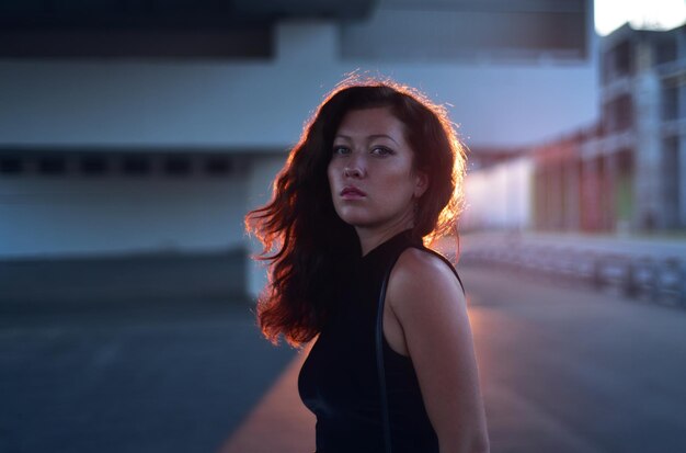 Side view portrait of woman standing against buildings in city