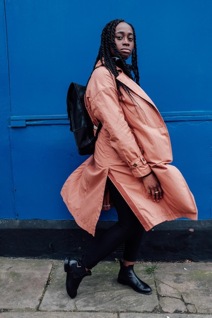 side view portrait of woman wearing overcoat while walking by wall