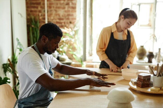 陶芸スタジオ コピー s で美術の授業を楽しみながら粘土を形作る若い黒人男性の側面図の肖像画