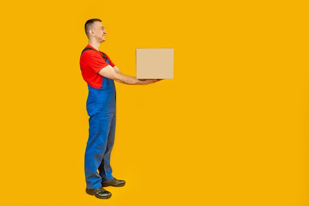 Side view of postman or deliveryman giving box isolated on yellow background fulllength portrait of courier with box in his hands copy space mock up