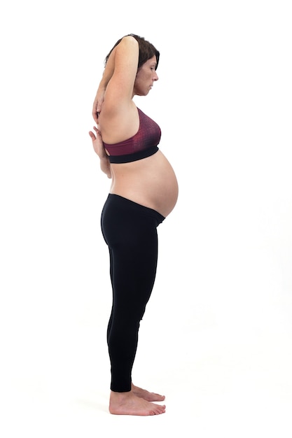 Side view of a pregnant woman doing standing exercises on white background