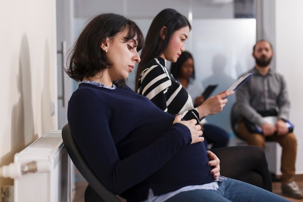 Photo side view of pregnant woman sitting at office