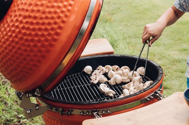 Side view of process of roasting champignons on grill