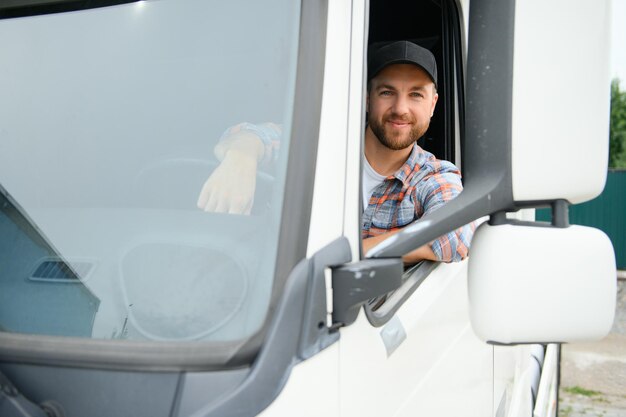 Photo side view of professional driver behind the wheel in truck's cabin