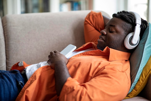 Side view relaxed black man listening to music at home