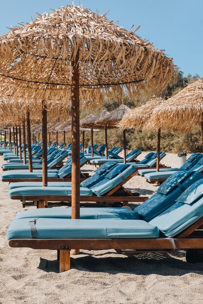 Photo side view of a row of empty blue sun beds under parasols on a beach in mykonos greece