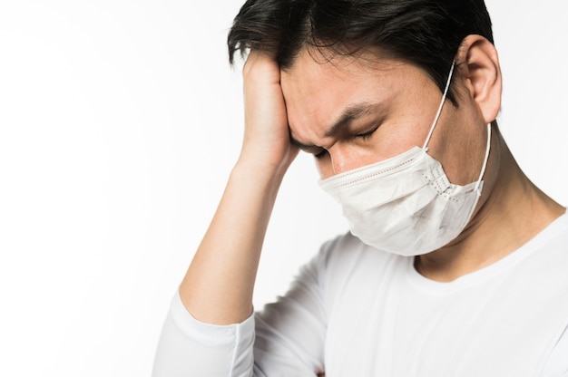 Photo side view of sad man with coronavirus wearing a medical mask