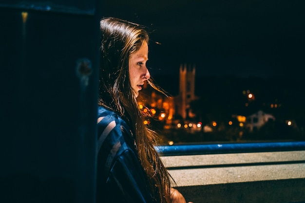 side view of sad thoughtful woman looking away at night