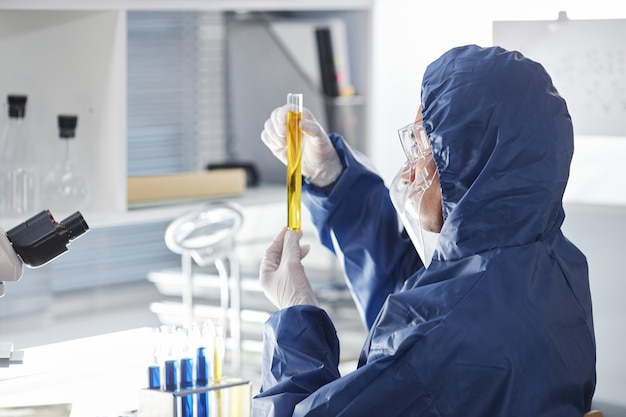 Вид сбоку ученого в защитном костюме в лаборатории, проводящего исследования