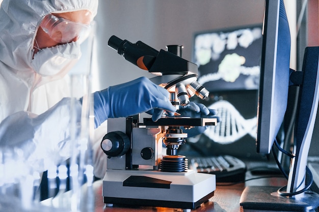 Side view of scientist in white protective uniform that works with coronavirus in laboratory