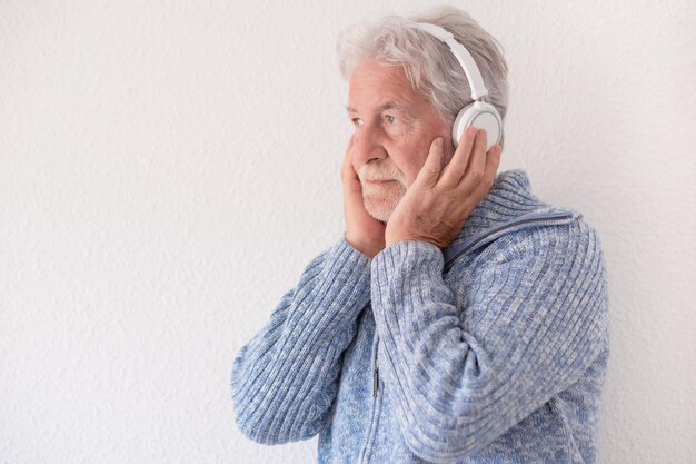 Side view of senior bearded man with headphones listening to music isolated on white background