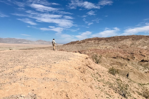 Side view of senior man standing on sand at desert against blue sky