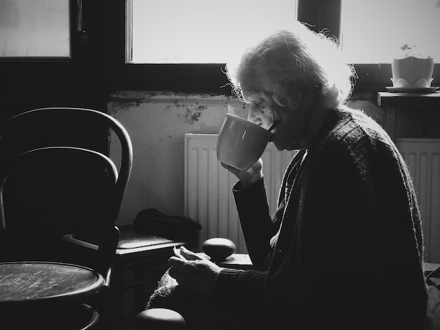 Photo side view of senior woman drinking coffee at home