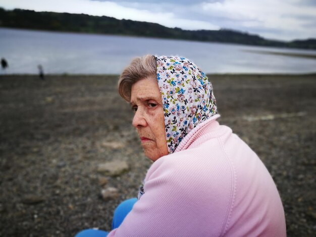 Photo side view of senior woman sitting at beach