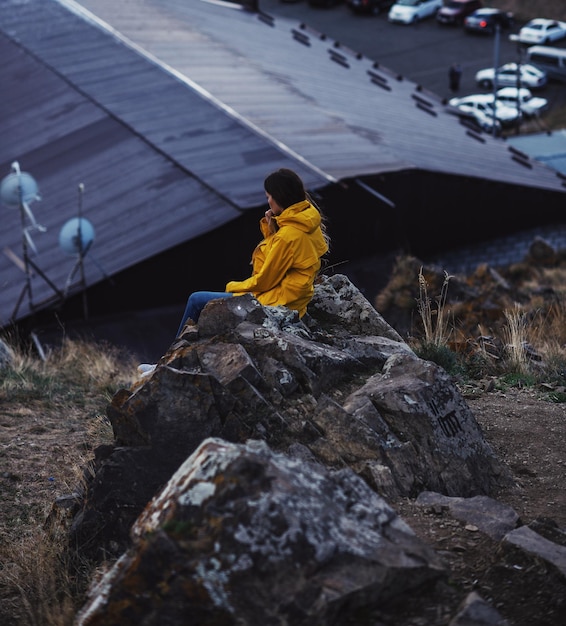 Photo side view of senior woman sitting on rock