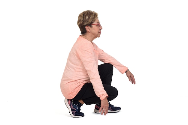 Side view of a senior woman squatting on white backgrond