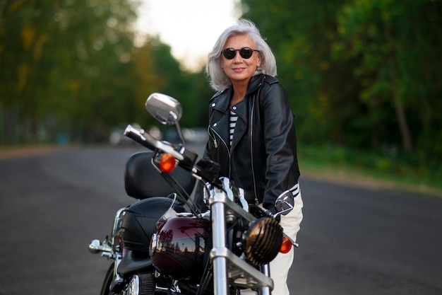 Photo side view  senior woman with motorcycle