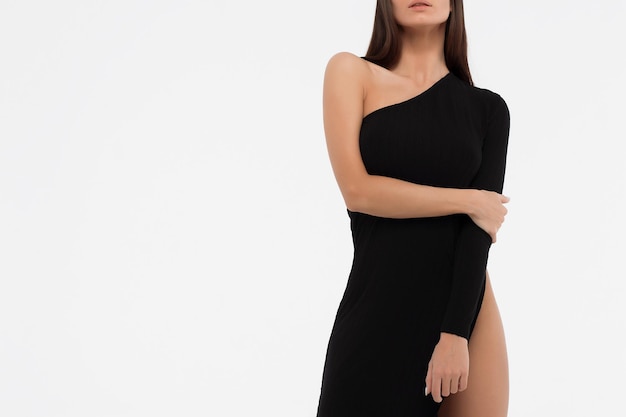 Side view of sensual lady in sexy black dress looking at camera against white background