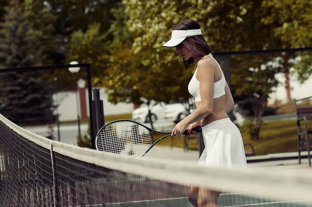 Side view of sensual young sportswoman in white sportswear and visor looking at camera