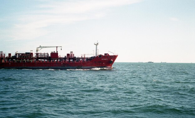 Photo side view of ship in calm sea against the sky