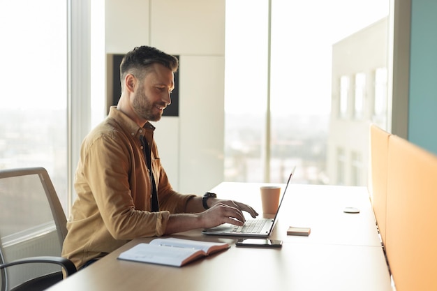 Side view shot of businessman typing on laptop at workplace