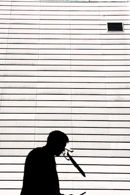 Foto vista laterale di un uomo in silhouette in piedi contro il muro