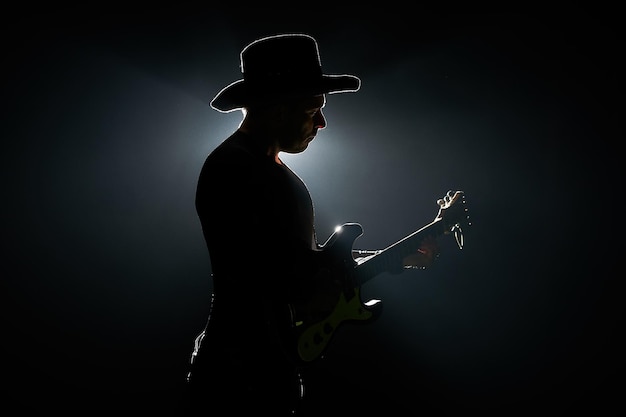 side view of silhouette mid adult man playing guitar against black background