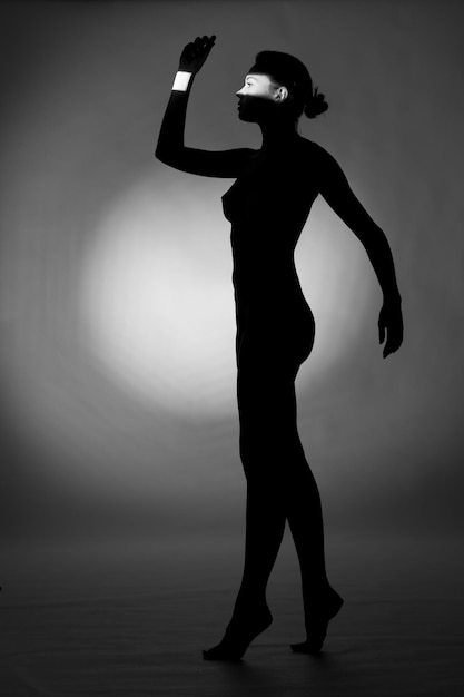 Side view of silhouette woman standing against gray background