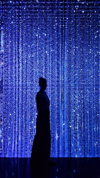 Side view of silhouette woman standing against illuminated curtain