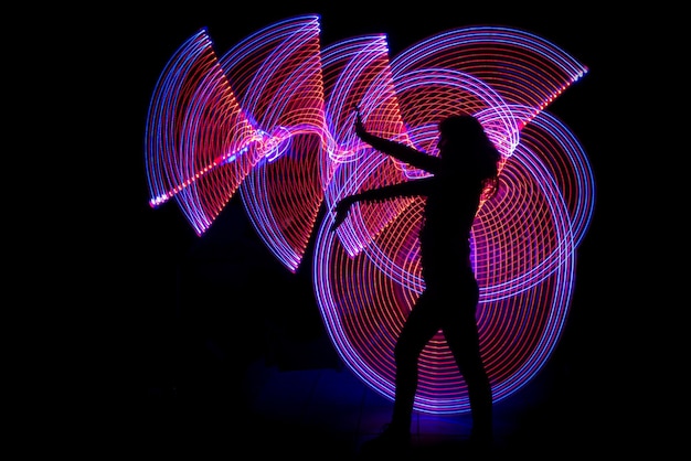 Photo side view of silhouette woman standing against light painting in darkroom