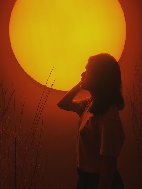 Side view of silhouette woman standing against sky during sunset