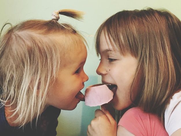 Photo side view of sisters eating frozen food