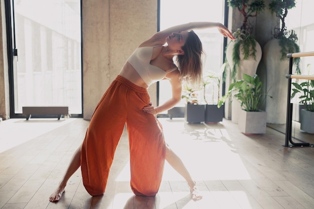 Side view of a slender woman Pilates and Yoga Exercise on a mat on the floor surrounded