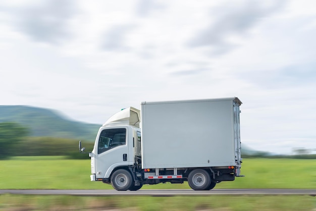 Photo side view of a small truck driving on a country road truck running on the road small truck on the road