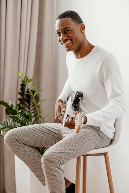 Foto vista laterale del musicista maschio di smiley che gioca chitarra elettrica