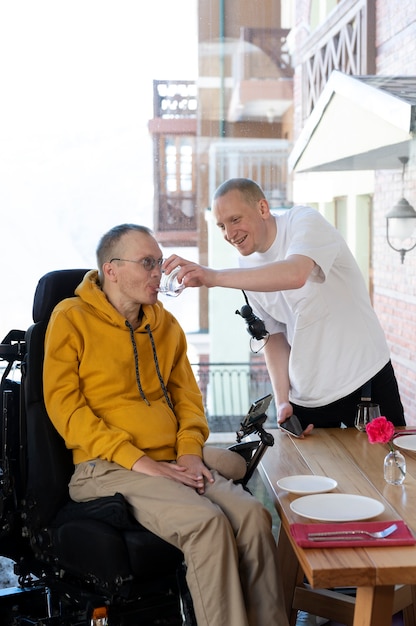 Photo side view smiley man helping friend drink water