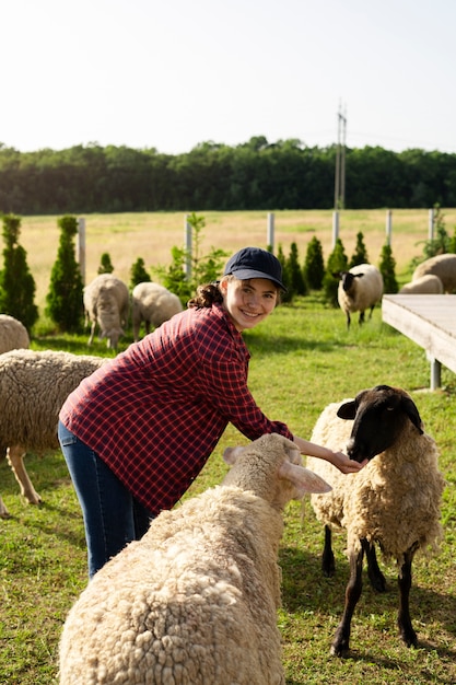 Photo side view smiley woman petting sheep