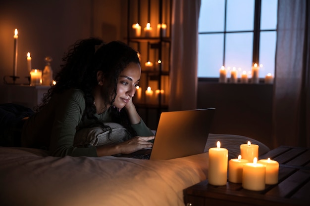 Foto donna sorridente di vista laterale con il computer portatile a letto