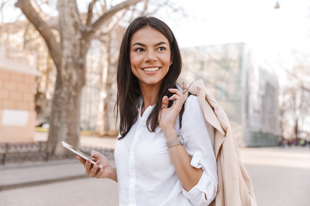 Side view of Smiling brunette woman in shirt holding jacket