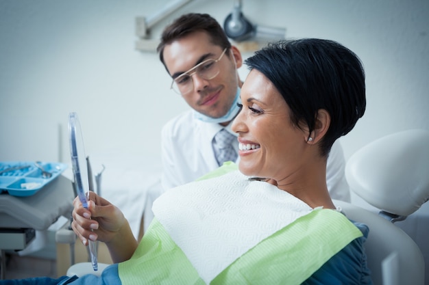 Photo side view of smiling female patient with dentist