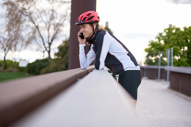 Foto vista laterale di un uomo sorridente che ascolta al telefono mentre è in piedi sul ponte