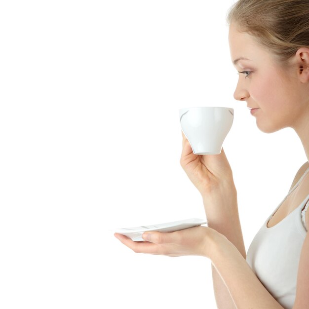 Side view of smiling woman with tea standing against white background