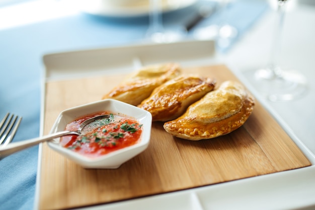 Side view on spanish pies empanadas with sauce on the restaurant table