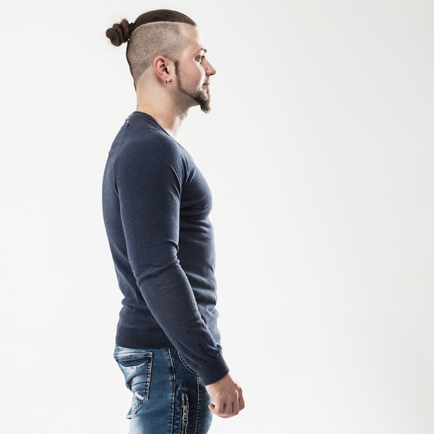 Photo side view - the sports guy - a bodybuilder in jeans and a t-shirt on a light wall . the photo has a empty space for your text