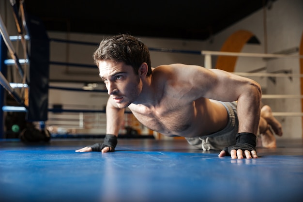 Side view of strong boxer doing push ups