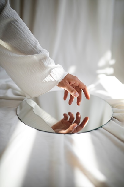 Студийный портрет сбоку с зеркалом, касающимся руки